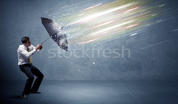 Business man defending light beams with umbrella concept Stock photo © ra2studio