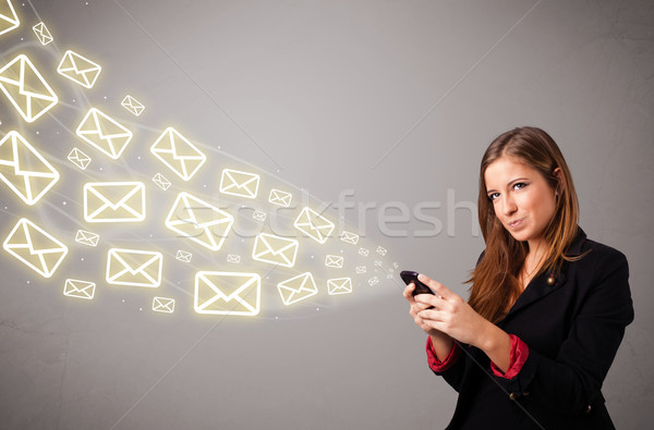 Stock photo: attractive young lady holding a phone with message icons