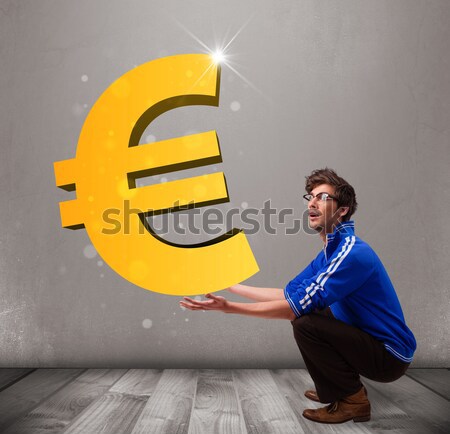 Good-looking boy holding a big 3d gold euro sign Stock photo © ra2studio
