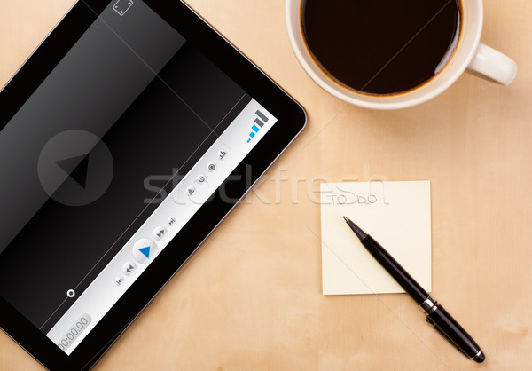 Workplace with tablet pc showing media player and a cup of coffee on a wooden work table closeup Stock photo © ra2studio