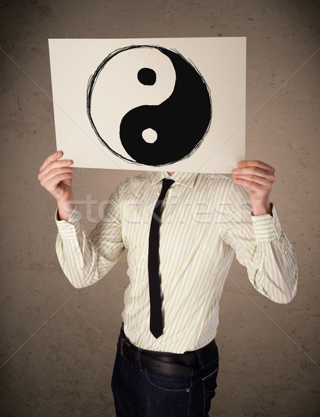 Businessman holding a paper with a yin-yang on it in front of hi Stock photo © ra2studio