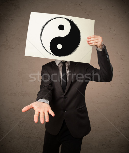 Businessman holding a paper with a yin-yang on it in front of hi Stock photo © ra2studio