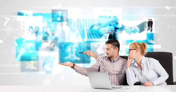 Stock photo: Business persons at desk with modern tech images at background
