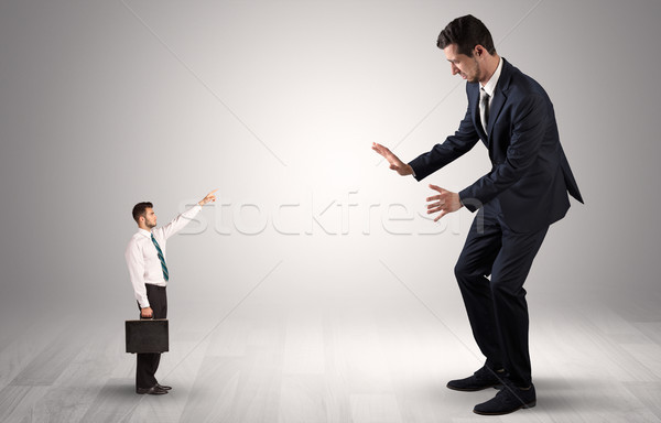 Small businessman pointing to a giant businessman Stock photo © ra2studio