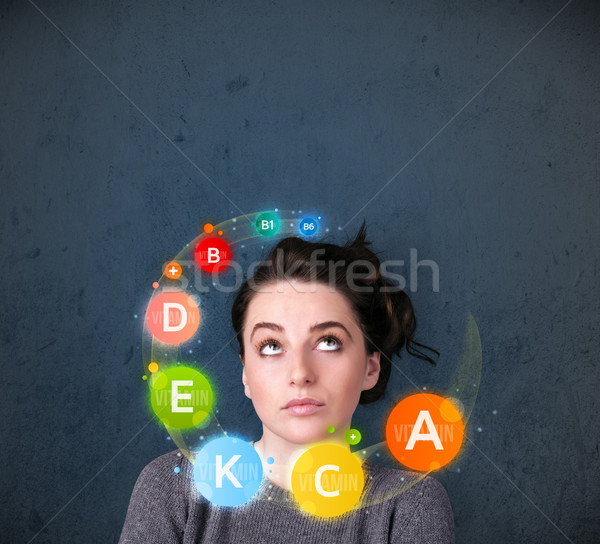 Young woman thinking with vitamins circulation around her head Stock photo © ra2studio