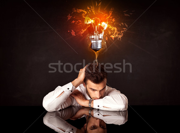 Businessman sitting under a blowing idea bulb Stock photo © ra2studio