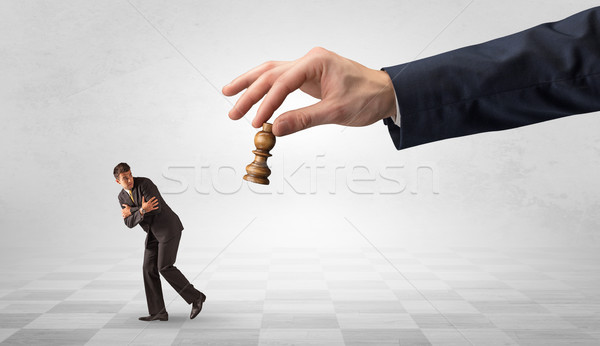 Stock photo: Small businessman running away from big hand with chessman concept