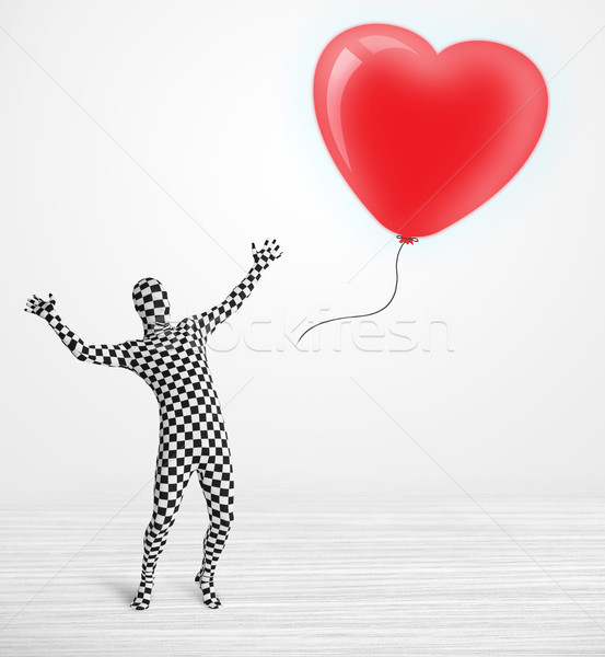 Cute guy in morpsuit body suit looking at a red balloon shaped heart Stock photo © ra2studio