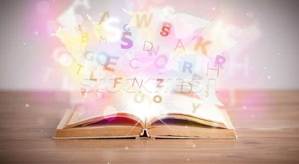 Open book with glowing letters on concrete background Stock photo © ra2studio