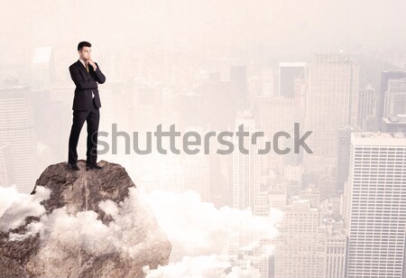 Happy businessman standing on stone top Stock photo © ra2studio