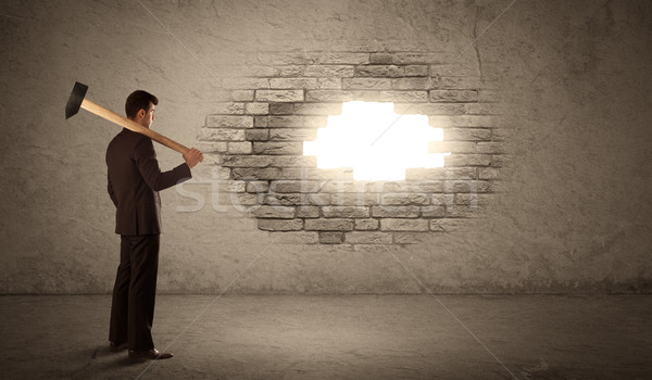 Business man hitting brick wall with hammer and opening a hole Stock photo © ra2studio