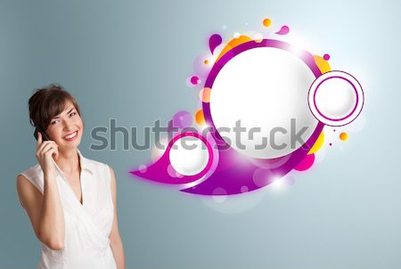 Stock photo: Pretty young woman presenting abstract speech bubble copy space and making phone call
