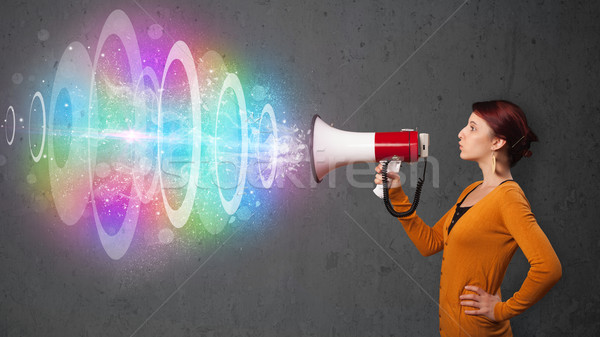 Cute young girl yells into a loudspeaker and colorful energy beam comes out Stock photo © ra2studio