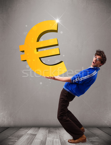 Good-looking boy holding a big 3d gold euro sign Stock photo © ra2studio