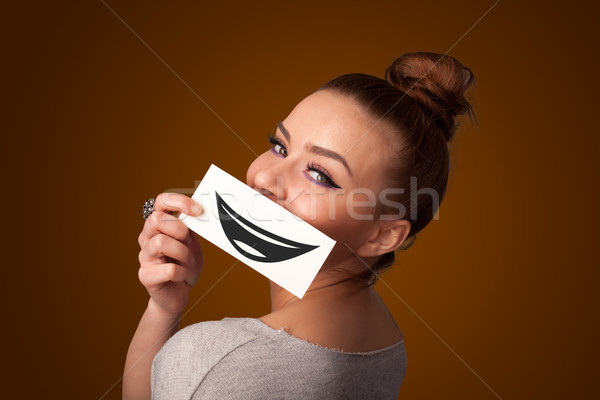 Happy pretty woman holding card with funny smiley Stock photo © ra2studio