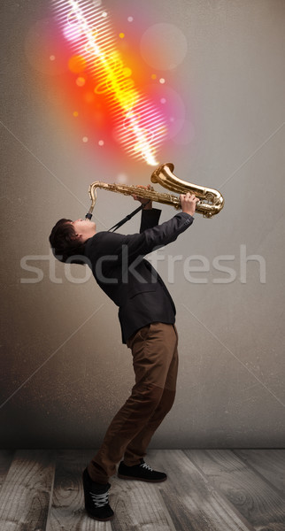 Young man playing on saxophone with colorful sound waves Stock photo © ra2studio