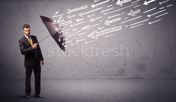 Business man standing with umbrella and drawn arrows hitting him Stock photo © ra2studio