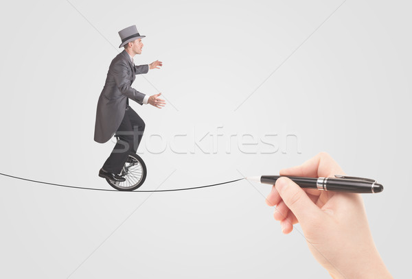 Stock photo: Businessman riding monocycle on a rope drawn by hand