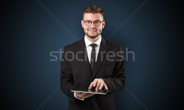 Businessman holding tablet with dark background Stock photo © ra2studio