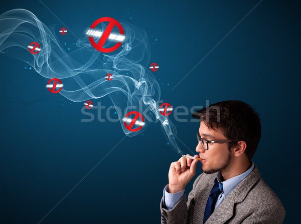 Attractive young man smoking dangerous cigarette with no smoking signs Stock photo © ra2studio