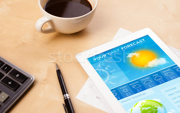 Workplace with tablet pc showing weather forecast and a cup of coffee on a wooden work table closeup Stock photo © ra2studio