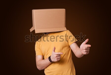 Young man gesturing with a cardboard box on his head Stock photo © ra2studio