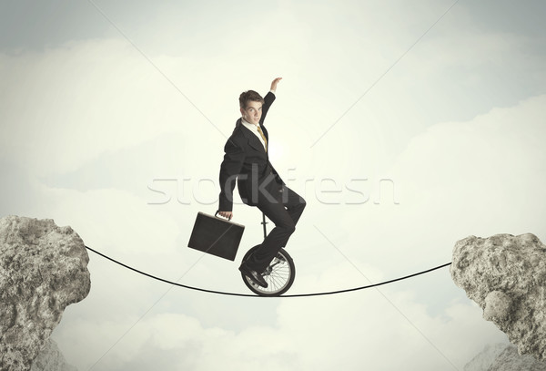 Brave business man riding an mono cycle between cliffs Stock photo © ra2studio