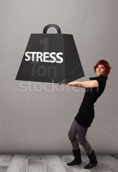 Young woman holding one ton of stress weight Stock photo © ra2studio