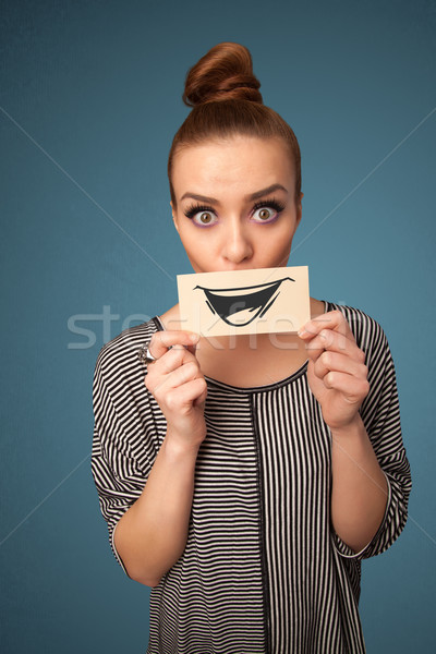 Stock photo: Happy cute girl holding paper with funny smiley drawing 