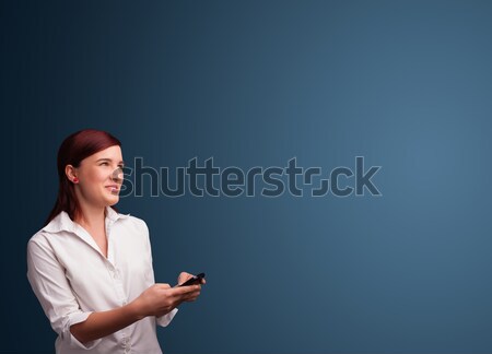 Young woman standing and typing on her phone with copy space Stock photo © ra2studio