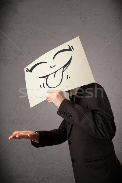 Businessman holding a paper with funny smiley face in front of h Stock photo © ra2studio