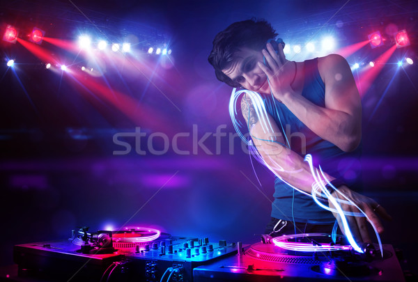 Stock photo: Disc jockey playing music with light beam effects on stage