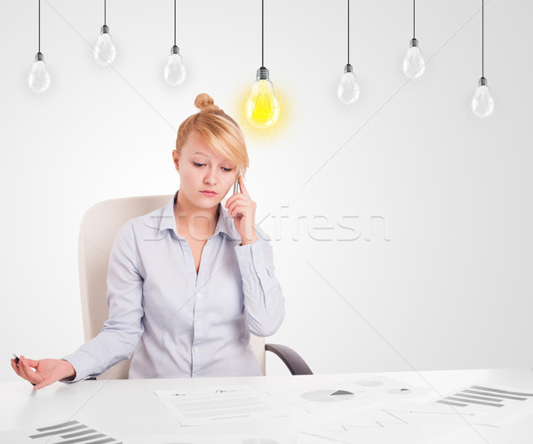 Business woman sitting at table with idea light bulbs Stock photo © ra2studio
