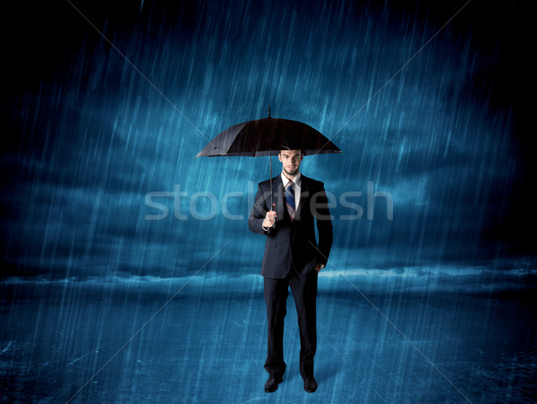 Business man standing in rain with an umbrella Stock photo © ra2studio