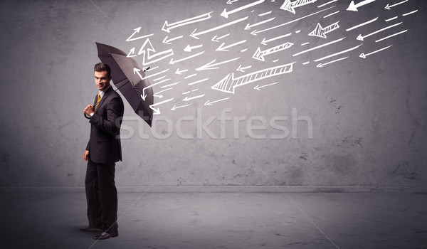 Business man standing with umbrella and drawn arrows hitting him Stock photo © ra2studio