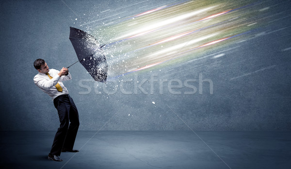 Business man defending light beams with umbrella concept Stock photo © ra2studio