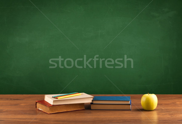 Stock photo: School items on desk with empty chalkboard