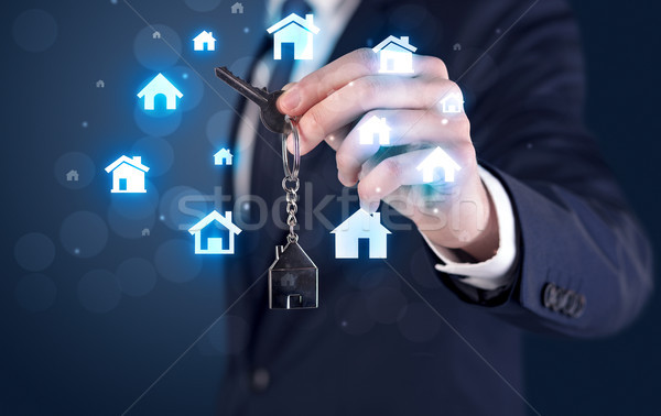 Businessman holding keys with houses around Stock photo © ra2studio