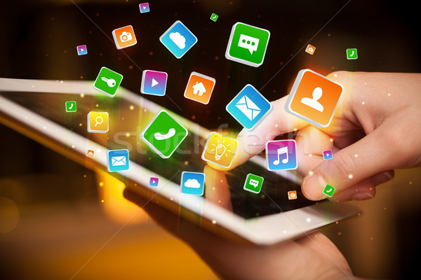 Hand using tablet with application icons flying around Stock photo © ra2studio