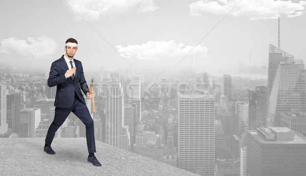 Suited karate man doing karate tricks on the top of a metropolitan city Stock photo © ra2studio
