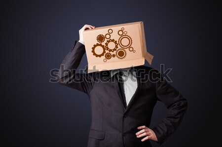 Young man gesturing with a cardboard box on his head with spur w Stock photo © ra2studio