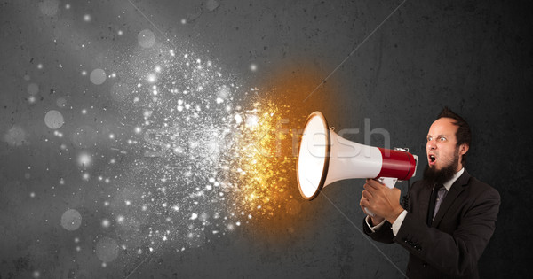 Guy shouting into megaphone and glowing energy particles explode Stock photo © ra2studio