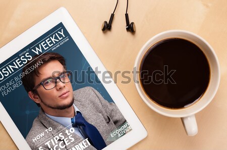 Workplace with tablet pc showing magazine cover and a cup of coffee on a wooden work table closeup Stock photo © ra2studio