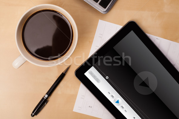 Workplace with tablet pc showing media player and a cup of coffee on a wooden work table closeup Stock photo © ra2studio