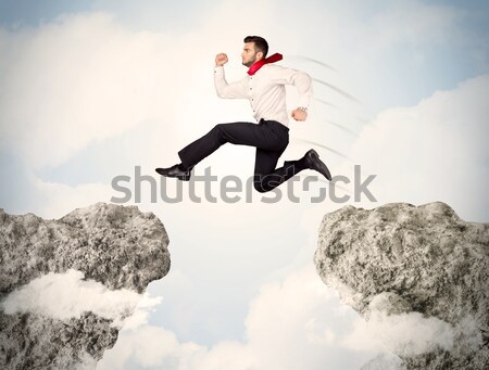 Happy business man jumping over a cliff  Stock photo © ra2studio