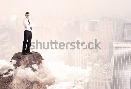 Happy businessman standing on stone top Stock photo © ra2studio