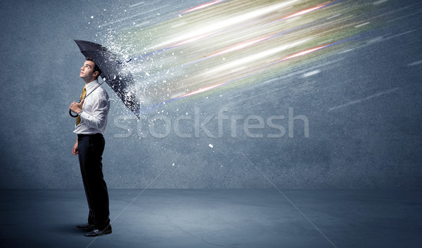 Business man defending light beams with umbrella concept Stock photo © ra2studio