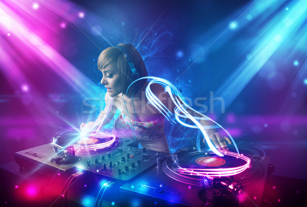 Energetic Dj girl mixing music with powerful light effects Stock photo © ra2studio