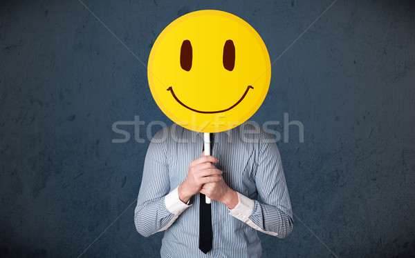 Businessman holding a smiley face emoticon Stock photo © ra2studio