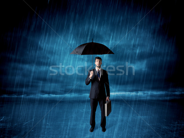 Business man standing in rain with an umbrella Stock photo © ra2studio